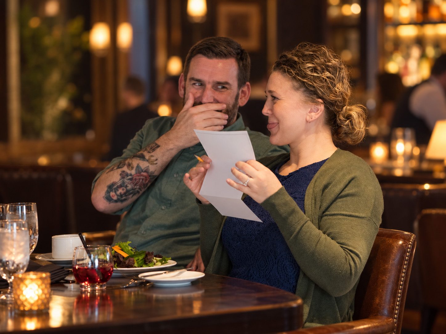 A couple compares answers at a candlelit dinner table