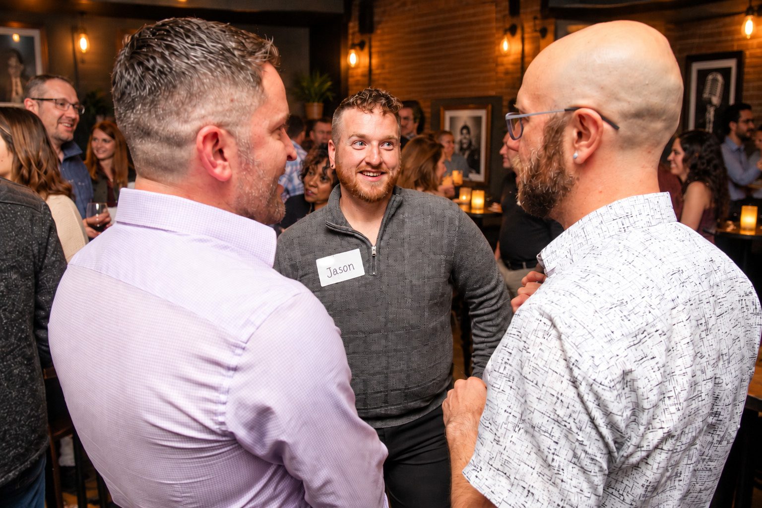 Guests in name tags chat and laugh in a brick-walled lounge